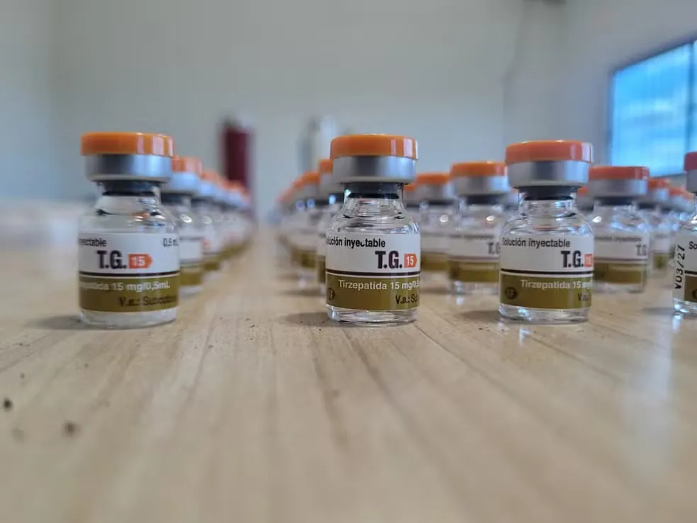 Frascos de TG 15 Tirzepatida 15 mg/0,5 mL com tampa laranja alinhados sobre bancada de madeira